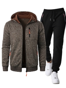 Detail of brown textured zip-up hoodie with orange accents and black jogger pants