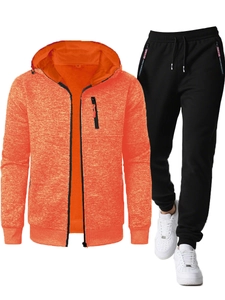 Detail view of men's orange fitness jacket and black knit joggers with textured fabric