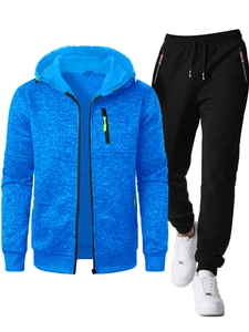 Detail of blue textured hoodie with green zipper pocket and black joggers with red trim