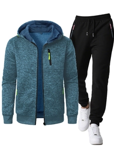 Detail of blue textured hooded sports jacket with neon green zipper and black joggers