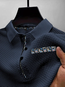 Detalle de polo azul oscuro con tejido de gofre, ribete de paisley y botones negros