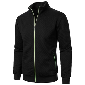 Detail of black stand-collar jacket with diamond texture and neon green zipper contrast