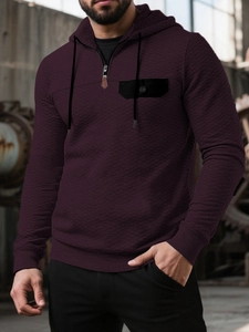 Detail eines burgunderroten Waffelstrick-Hoodies mit Viertelreißverschluss und Brusttasche