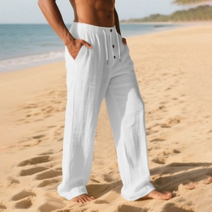 Detail of white linen trousers with drawstring waist and three wooden buttons on beach