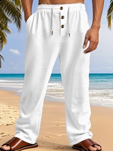 Detail of white cotton linen beach pants with drawstring waist and brown button accents