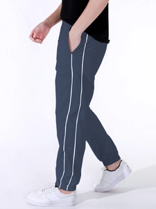 Detail of navy blue parachute pants with side white stripes and elastic cuffs