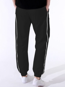 Detail of black jogger pants featuring contrast white side stripes and elastic cuffs