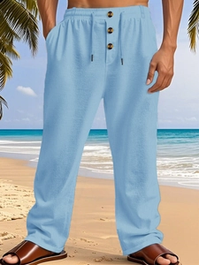 Detail of light blue linen trousers featuring elastic waistband and drawstring on beach
