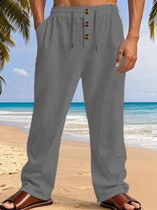 Detail of men's linen pants featuring elastic drawstring waist and decorative wood buttons