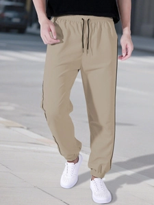 Detail of khaki jogger pants featuring elastic waistband with adjustable black drawstring