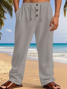 Detail of men's linen pants featuring elastic drawstring waist and wooden button accents
