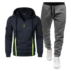 Détail du survêtement gris foncé avec fermeture éclair vert fluo et pantalon de jogging