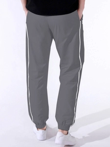 Detail view of men's dark grey cargo pants with white side stripes and cuffed hems