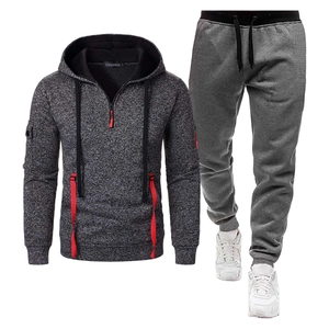 Détail de la veste à capuche grise et du jogging avec accents rouges et poche zippée