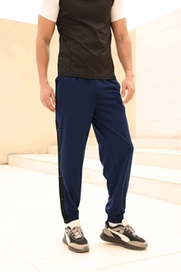 Detail of dark blue men's joggers with black side stripes and metal snap buttons