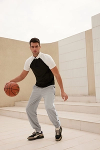 Detail view of men's loose tearaway basketball pants with side buttons and striped patterns