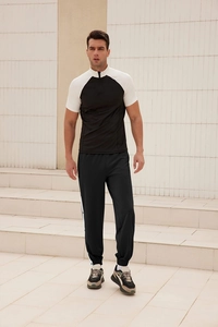 Detail of men's buttoned track pants with white side stripes and elastic ankle cuffs