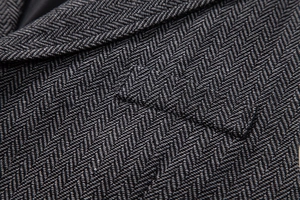 Detail of grey herringbone wool vest showing lapel texture and a flap pocket