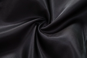 Macro detail of high-quality black satin fabric with smooth silk texture and soft drapery
