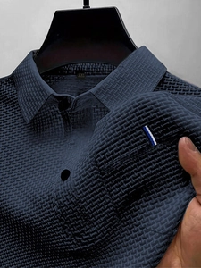 Primo piano della polo blu navy con trama a nido d'ape e dettaglio taschino a righe
