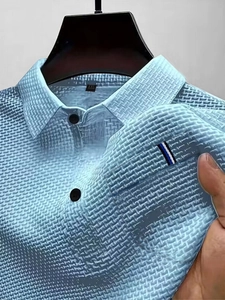 Détail du polo bleu clair avec texture gaufrée et rayure tricolore sur la poche