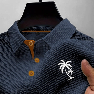 Détail d'un polo bleu marine en maille gaufrée avec col contrasté orange et palmier