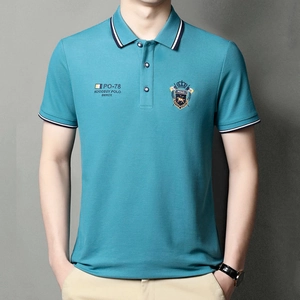 Detailed view of lake blue polo shirt with embroidered badge and striped collar accents
