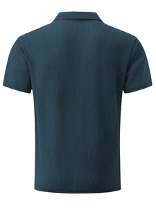 Detail of navy blue polo shirt featuring textured waffle knit fabric and a neat polo collar