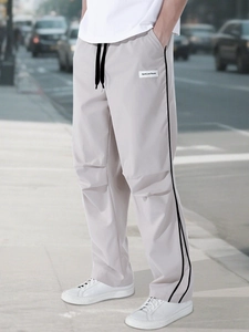 Detail of light grey cargo pants with black side stripes and drawstring waist