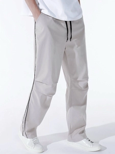 Close-up of men's casual grey parachute pants showing waist drawstring and side stripe