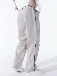 Detail view of men's parachute pants showing straight-cut fit and black side stripe detail