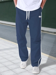 Detailed view of dark blue athletic cargo pants featuring white side stripes and drawstring