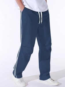 Detail of navy blue parachute pants showing elastic waistband with white drawstring