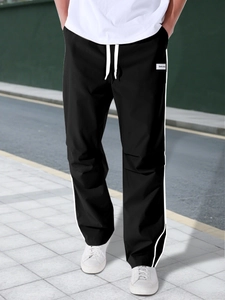 Close-up of black cargo pants with side stripes and adjustable drawstring waist