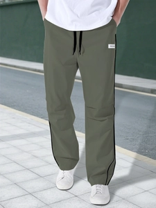 Detail of olive green cargo pants with black side stripes and drawstring waistband