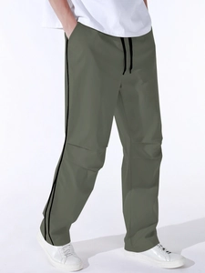 Detail of olive green cargo pants featuring black side stripes and drawstring waist