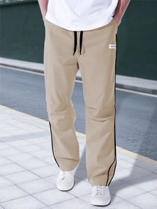 Detail of khaki jogger pants with side stripes, drawstring waist and brand patch