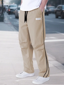 Detail of khaki cargo pants with black side stripes and sports leisure label