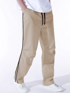 Detail of khaki jogger pants featuring side stripes and ergonomic knee seams for men