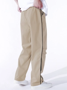 Detail of khaki cargo pants featuring black piping accents and a loose straight cut design