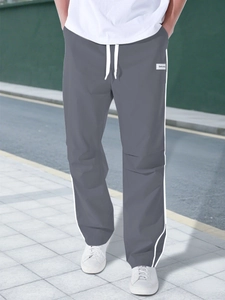 Close-up of grey tactical jogger pants with white side stripes and drawstring waist