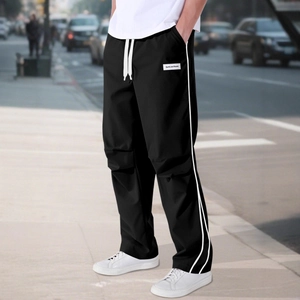 Men's black street-style parachute pants with white side stripes and drawstring