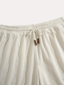 Detail of white corduroy shorts with elastic waist, drawstring and brown leather tips