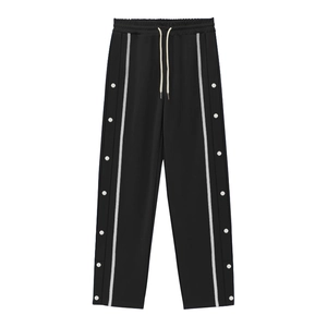 Detail of black sports trousers with white side stripes and side snap button closures