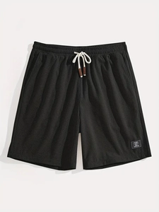 Detail of black waffle knit shorts featuring elastic drawstring waist and woven cord