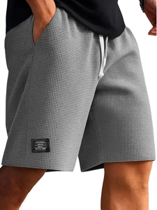 Dettaglio macro dei pantaloncini da uomo grigi in maglia waffle con texture e coulisse