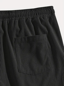Detail of black corduroy shorts showing elastic waistband and ribbed fabric texture