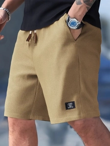 Detail of dark khaki waffle knit fabric and drawstring waistband on men's casual shorts