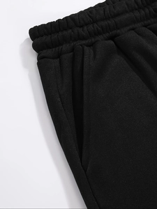 Detail view of black jogging pants featuring an elastic drawstring waist and side pockets