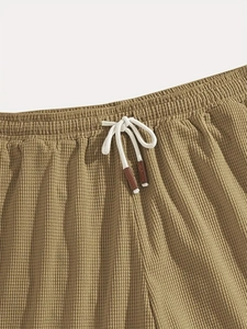 Detail of waffle knit shorts waist featuring elastic band and cord with leather tips